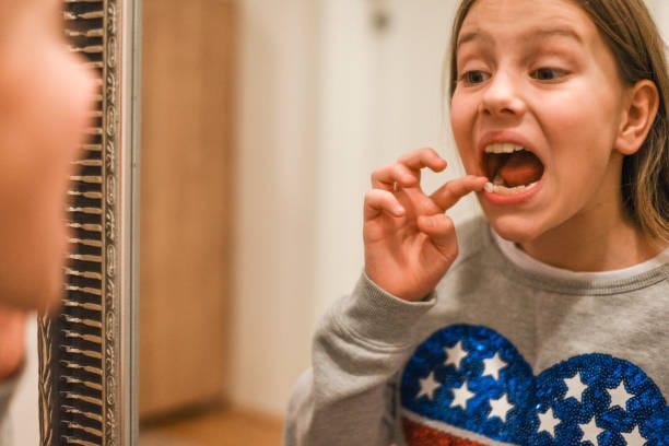 Little girl pulling out her loose tooth
